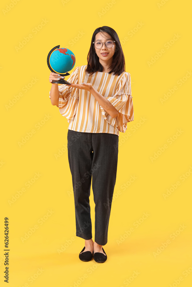 Female Asian Geography teacher with globe on yellow background