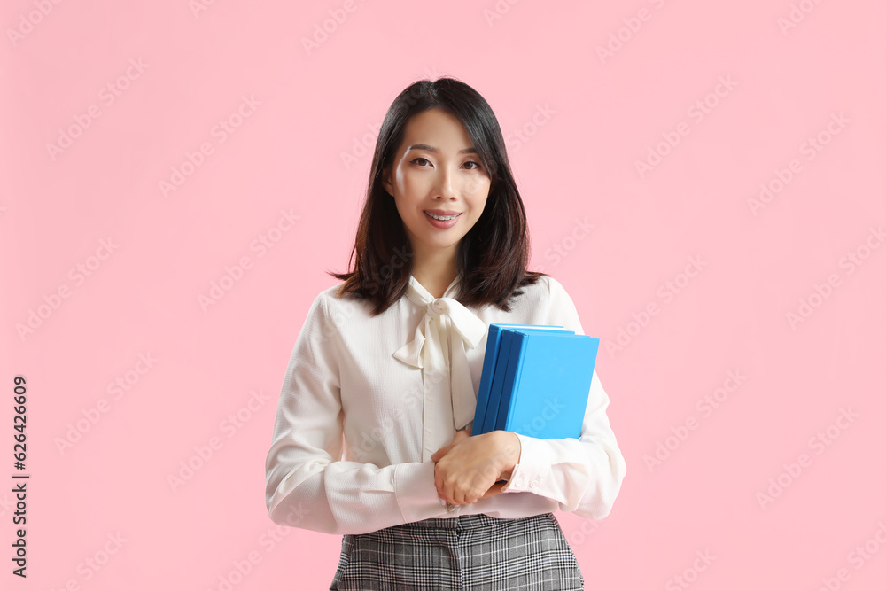 Asian Literature teacher with books on pink background