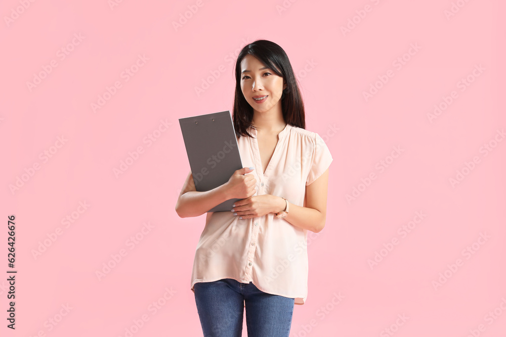 Female Asian teacher with clipboard on pink background