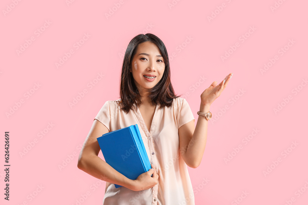 Asian Literature teacher with books on pink background