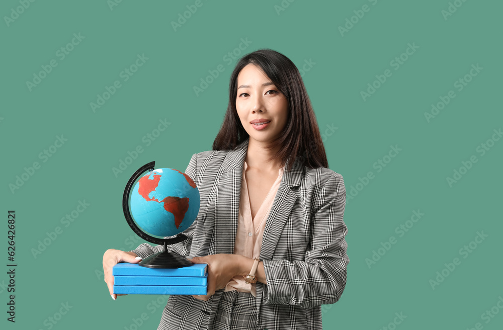 Asian Geography teacher with globe and books on green background