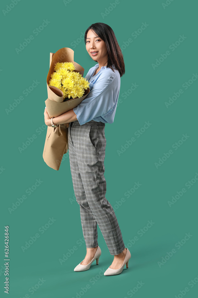 Female Asian teacher with bouquet of flowers on green background