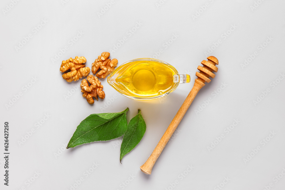 Gravy boat of sweet honey with walnut and leaves on grey background