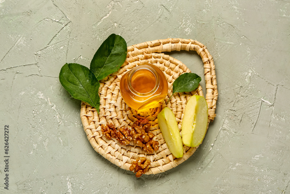 Jar of sweet honey with apple and walnut on grey background