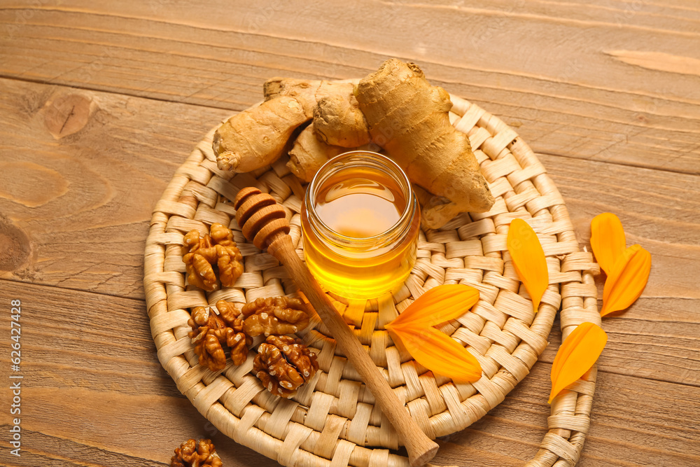 Jar of sweet honey with walnut and ginger on wooden background