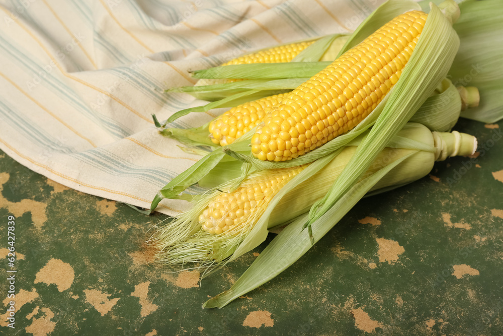 Fresh corn cobs on green background