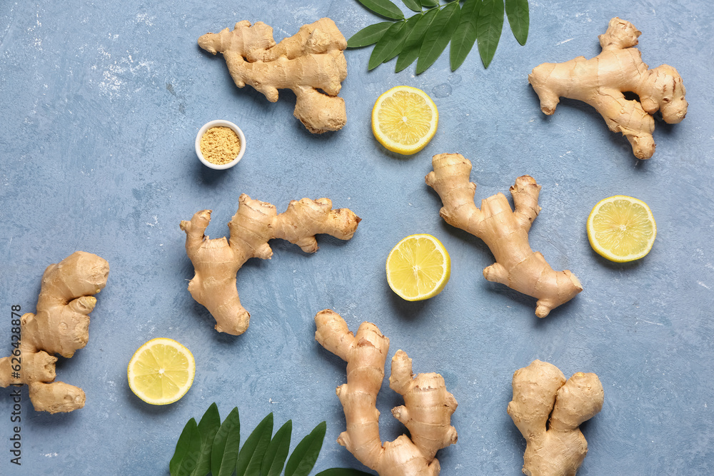 Fresh ginger roots with slices of lemon and leaves on blue background