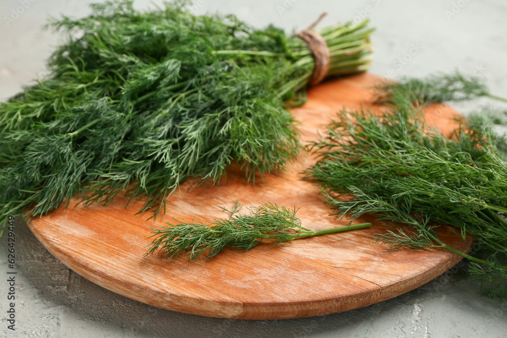 Wooden board with fresh dill on grey background