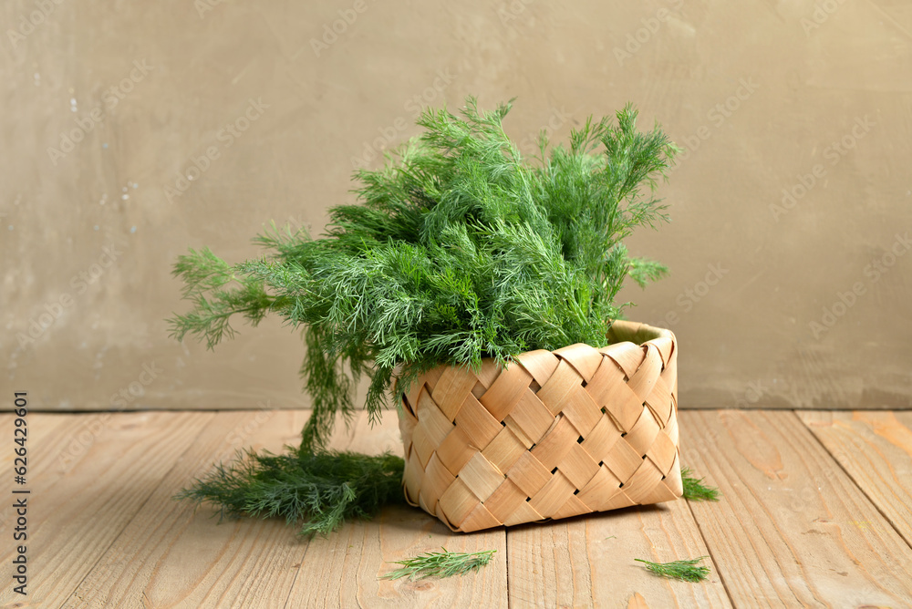 Wicker basket with fresh dill on table