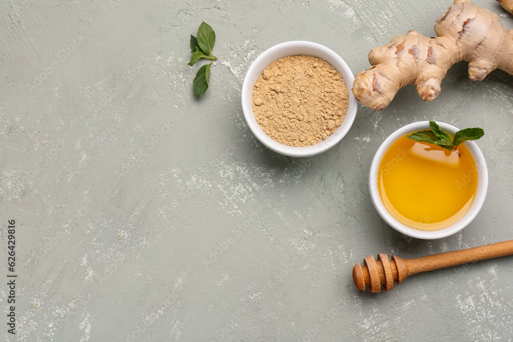 Fresh ginger root and bowl with dried powder on grey background