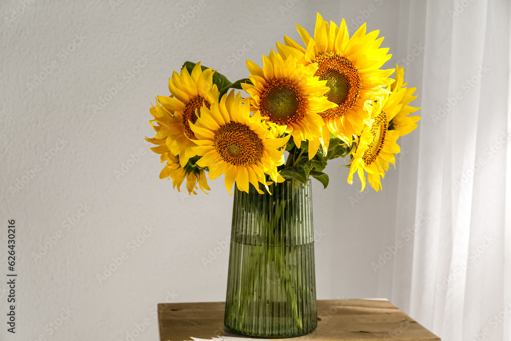 Vase with beautiful sunflowers on table in room, closeup