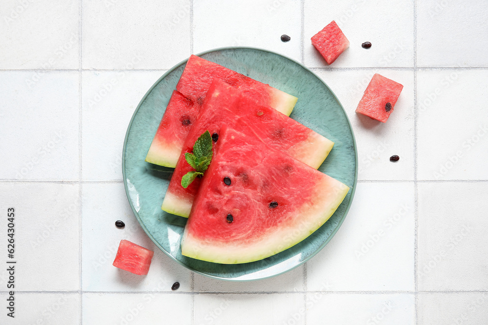 Plate with pieces of ripe watermelon on light tile background