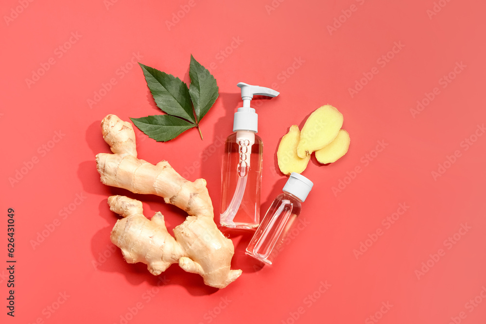 Bottles of ginger cosmetic oil and leaves on red background