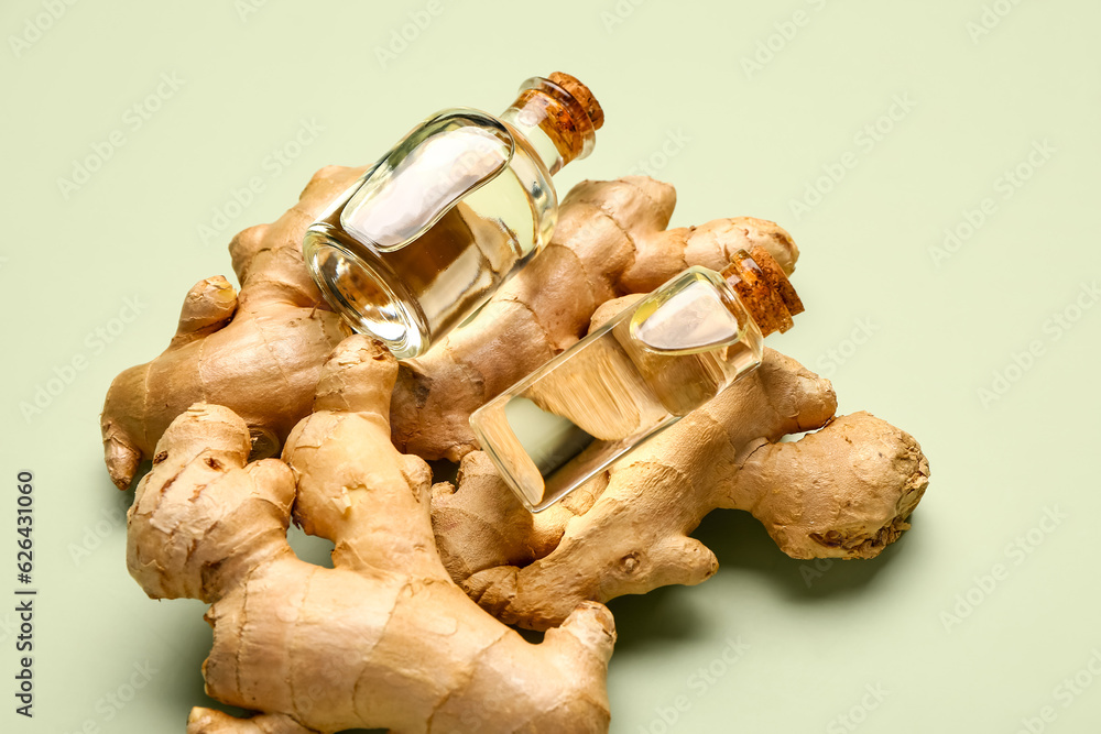 Bottles of ginger cosmetic oil on green background