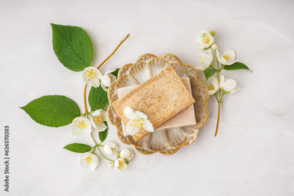 Plate with soap bars and beautiful jasmine flowers on light background