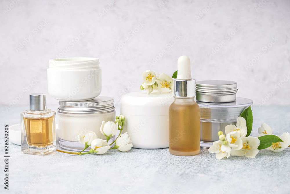 Set of different cosmetic products and beautiful jasmine flowers on light background