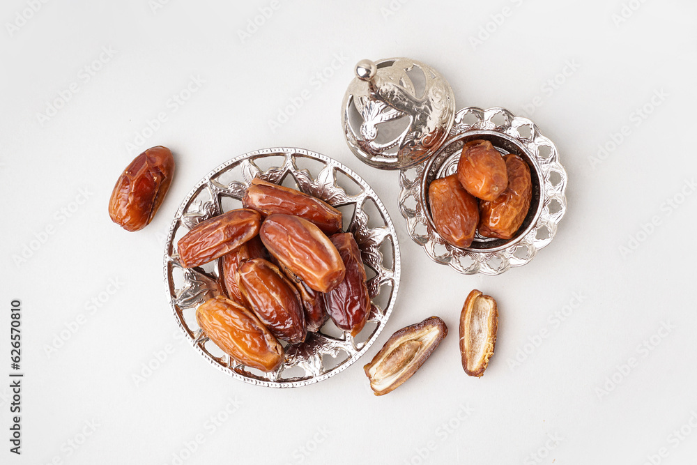 Bowls with dried dates on light background