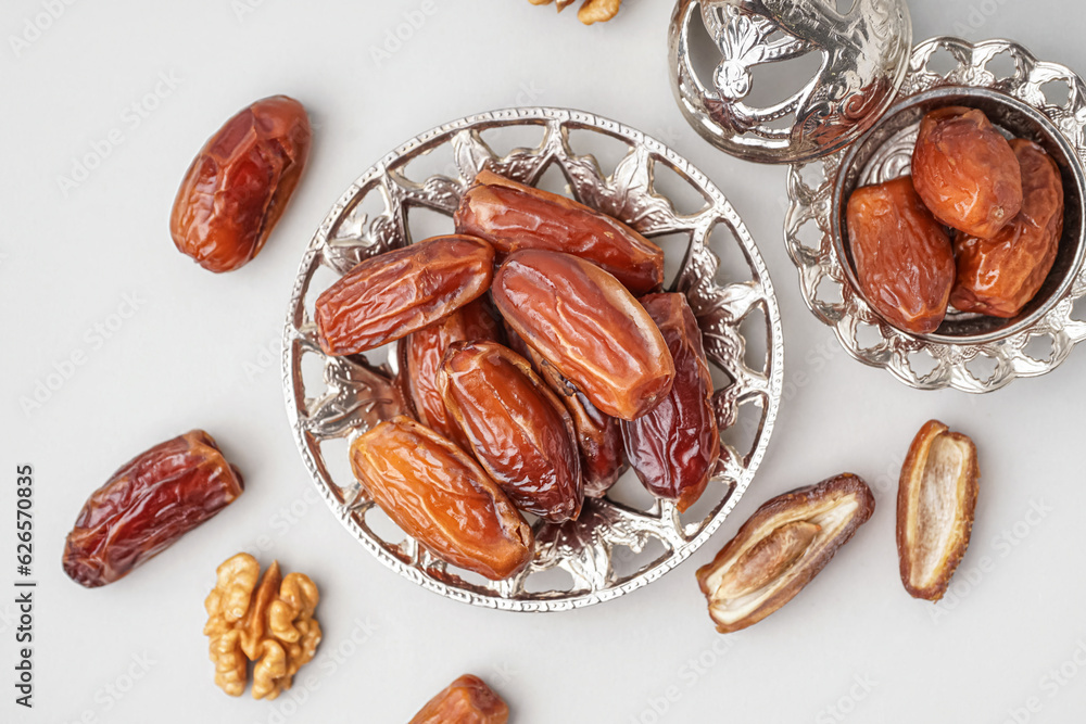 Bowls with dried dates on light background