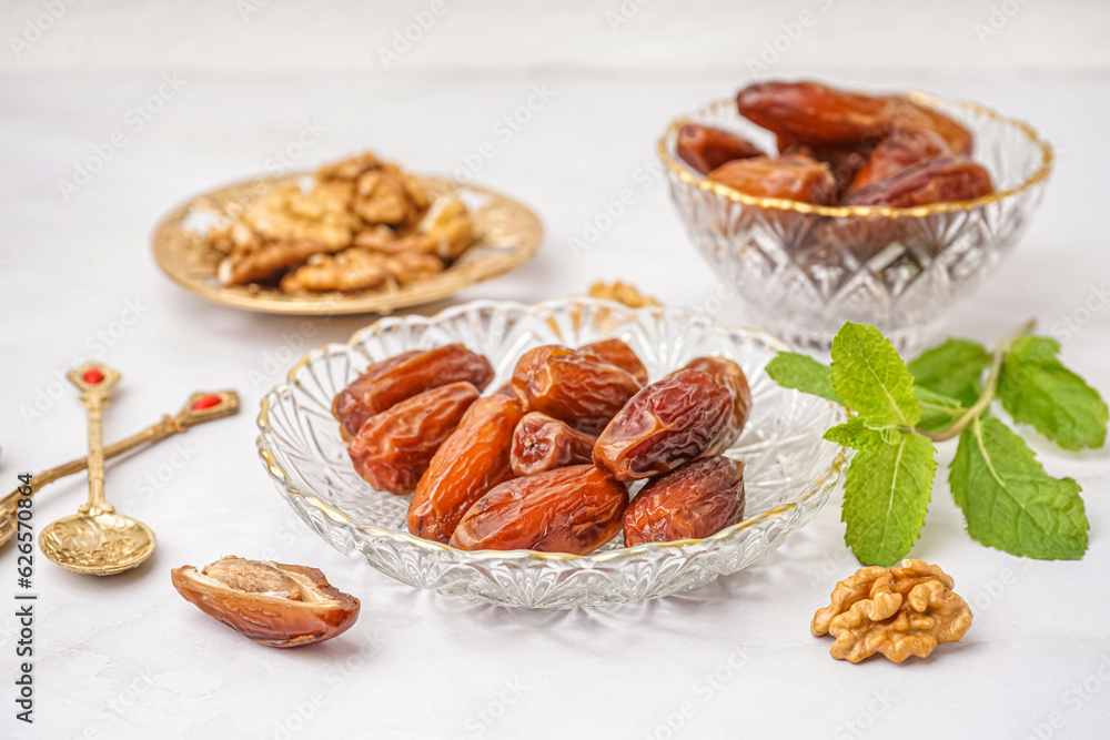 Bowl with dried dates on light background