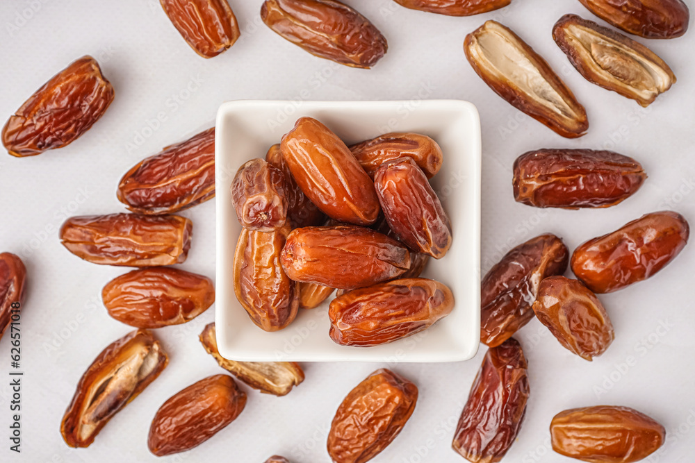 Bowl with dried dates on light background