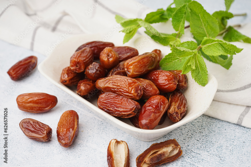 Bowl with dried dates on light background