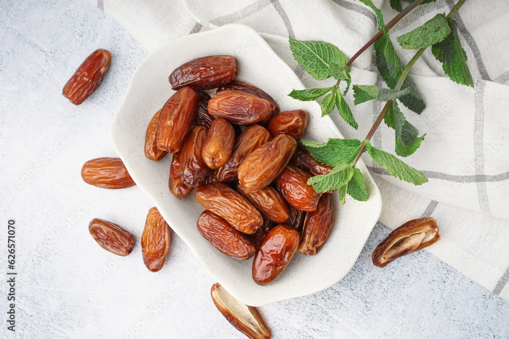 Bowl with dried dates on light background