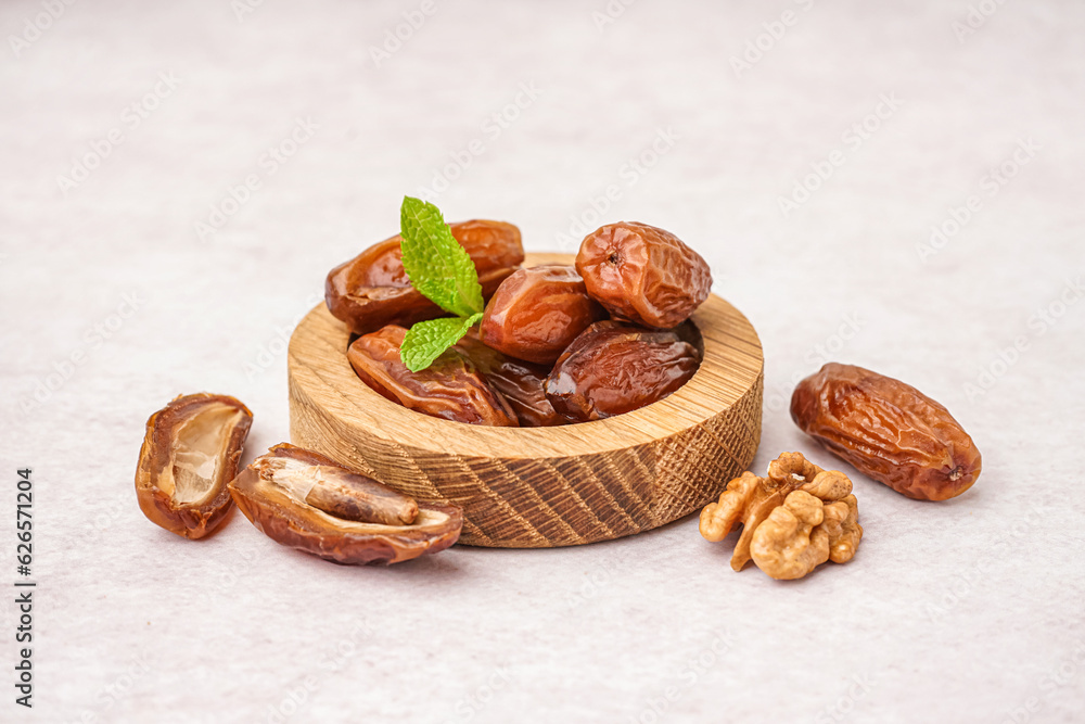 Bowl with dried dates on light background