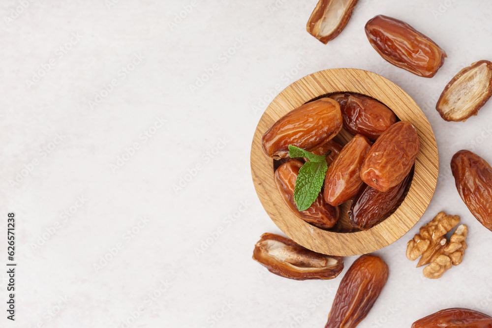 Bowl with dried dates on light background