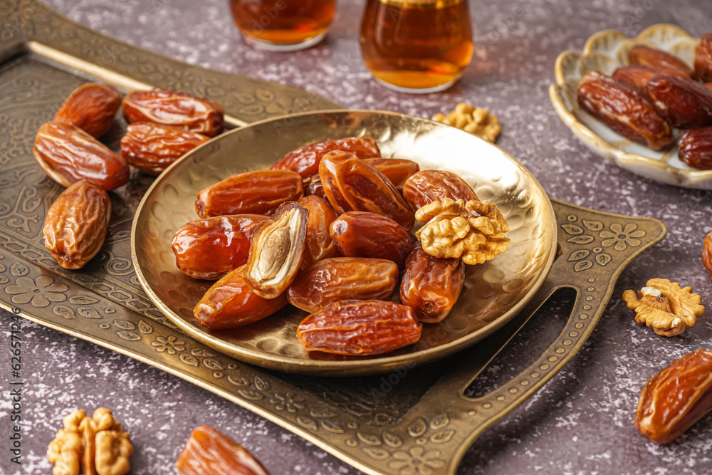 Plate with dried dates and nuts on grey background