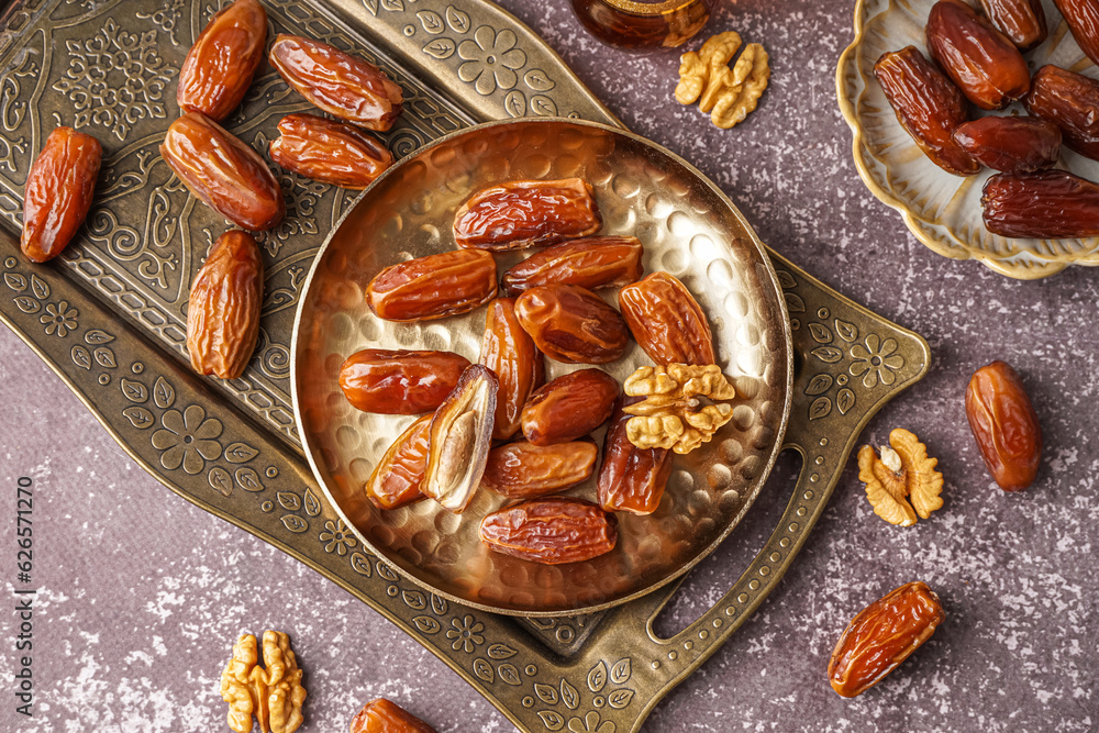 Plate with dried dates and nuts on grey background