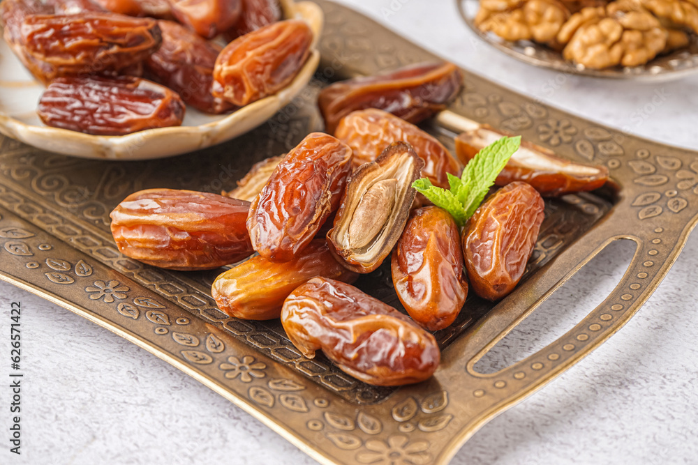 Tray with dried dates on light background