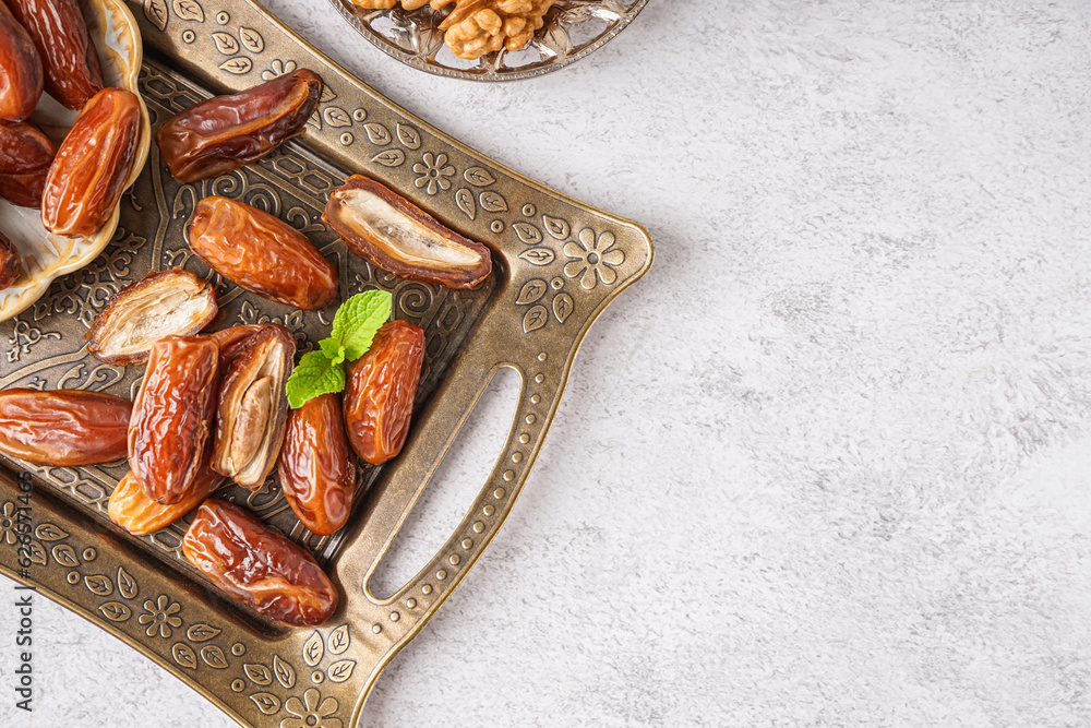 Tray with dried dates on light background