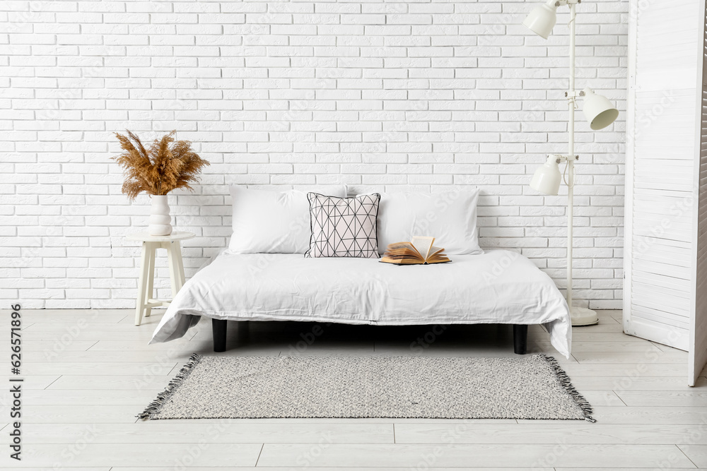 Interior of light bedroom with cozy bed and stylish carpet