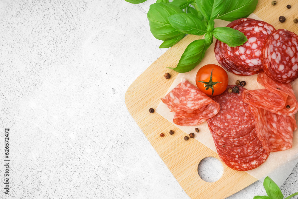 Slices of tasty salami on light background