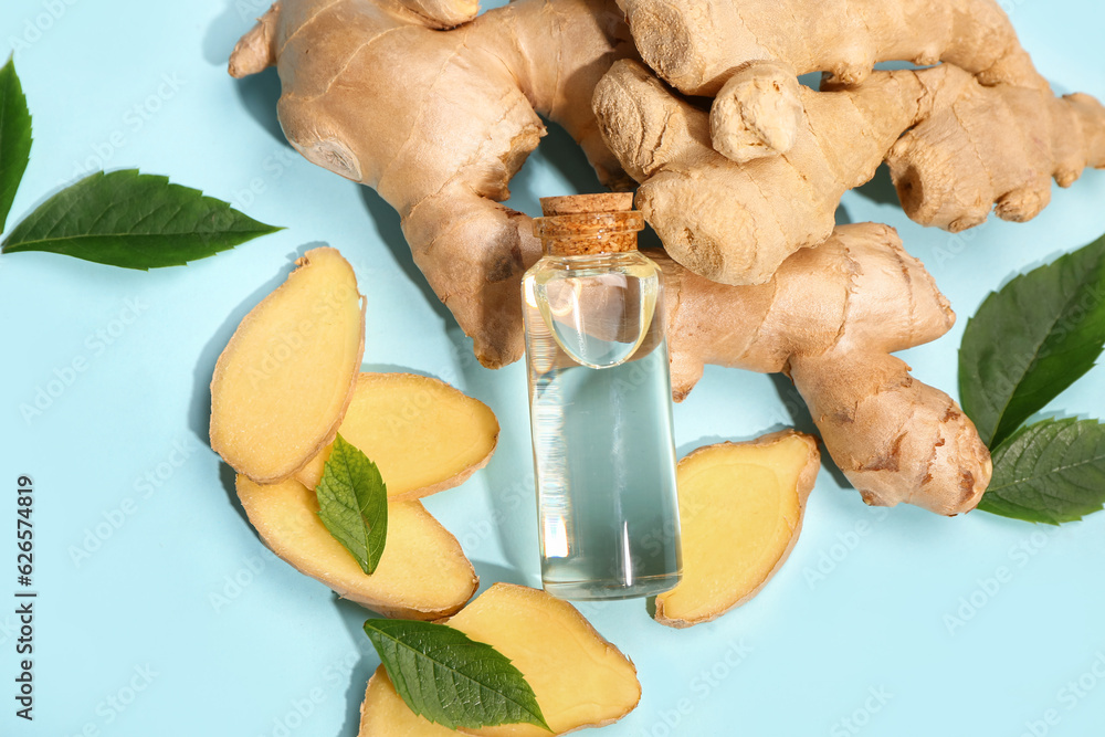 Bottle of ginger cosmetic oil and leaves on blue background