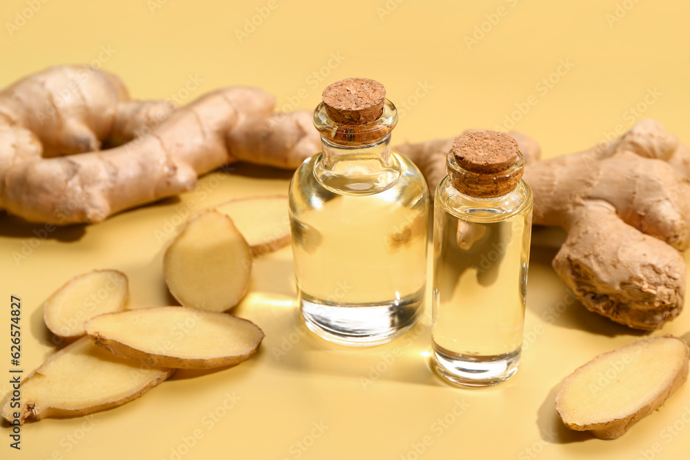 Bottles of ginger cosmetic oil on yellow background