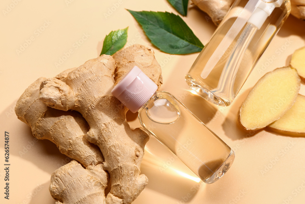 Bottles of ginger cosmetic oil and leaves on yellow background