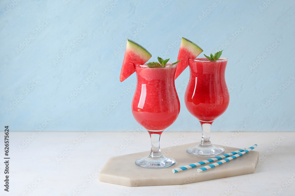 Board with glasses of tasty watermelon juice and mint on white table