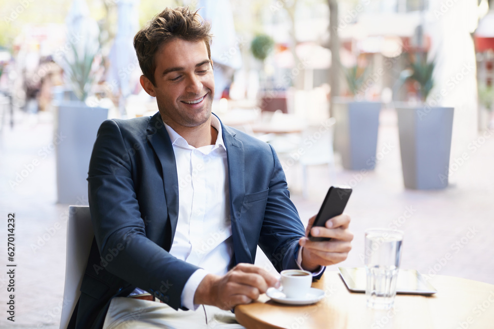 Shes on the way....Shot of a young businessman reading a text while sitting at an outdoor cafe.