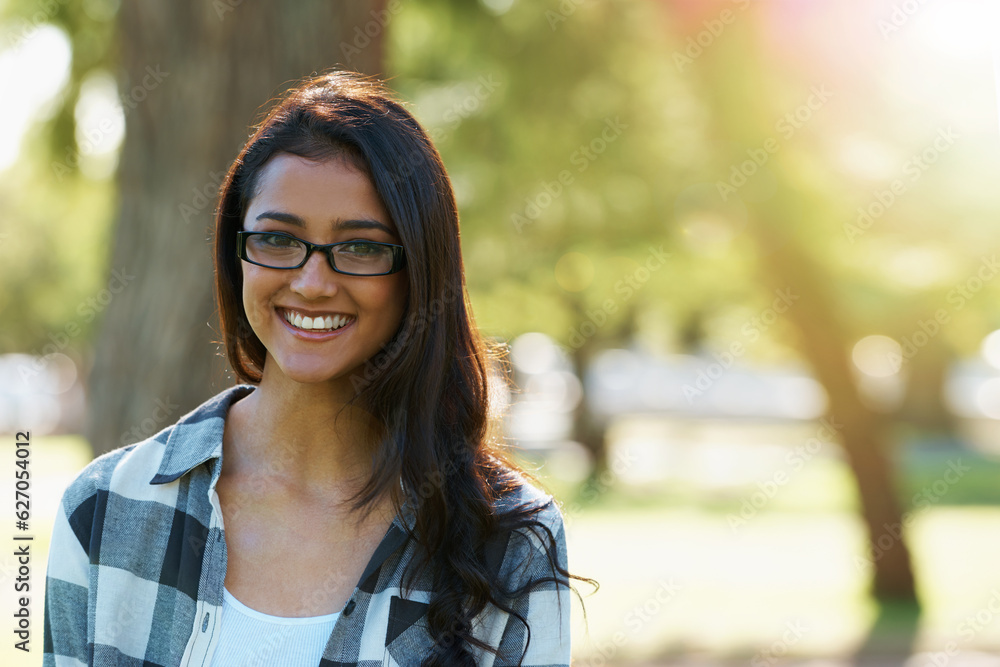 Relaxed beauty. A beautiful young woman wearing glasses standing in a park.