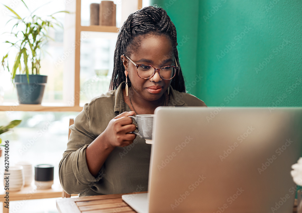 Coffee is the ultimate bloggers fuel. Shot of a young woman having coffee and using a laptop at a ca