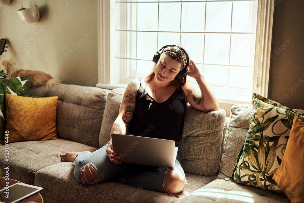 Sundays are for marathon movie streaming sessions. Shot of a young woman using a laptop and headphon