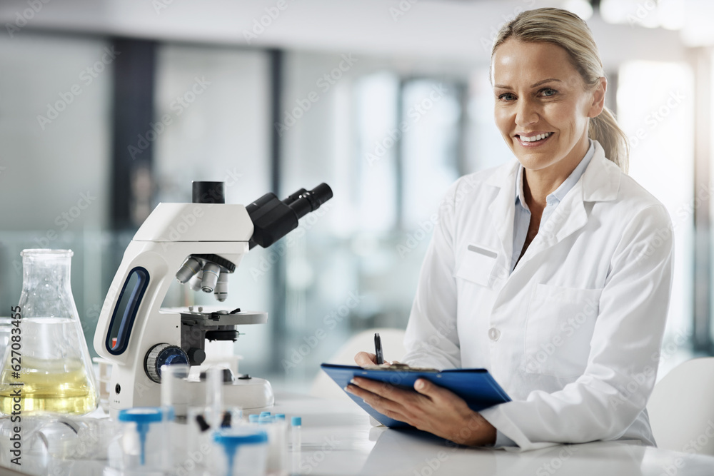 Im here to cure. Cropped portrait of an attractive mature female scientist taking down notes while d