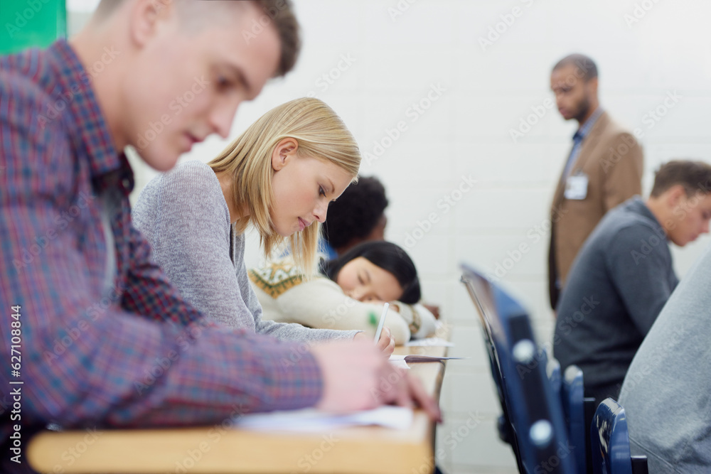 This lecture hall is completely focused. Shot of a group of university students writing an exam.