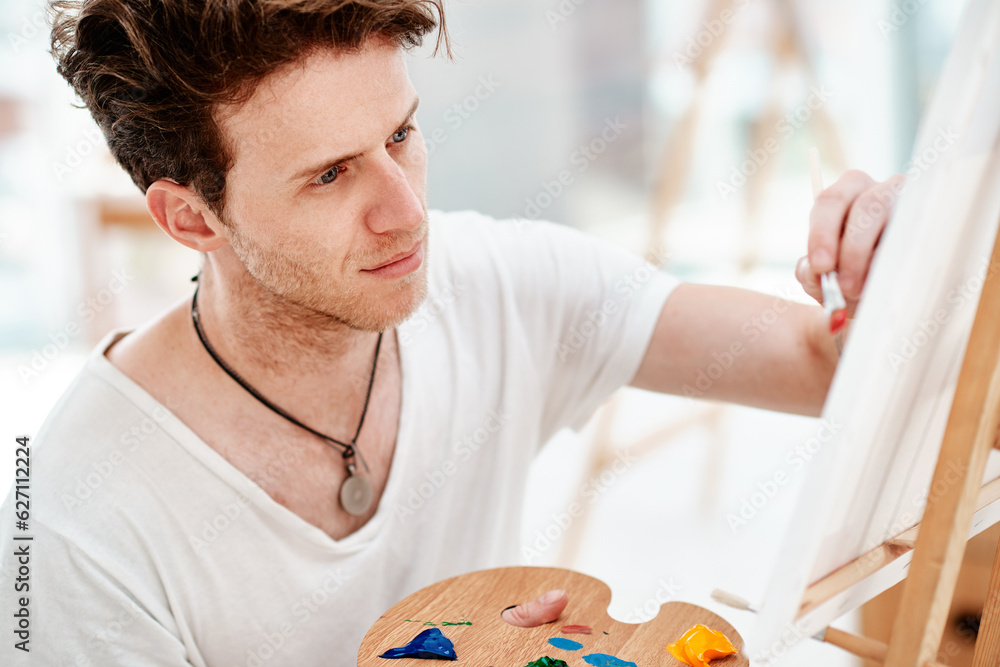 Everything you can imagine is real. Cropped shot of a handsome young artist sitting alone and painti