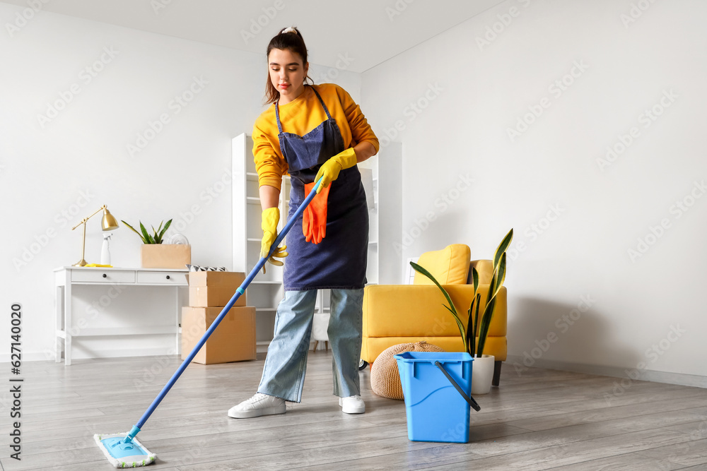 Young woman mopping floor in her house