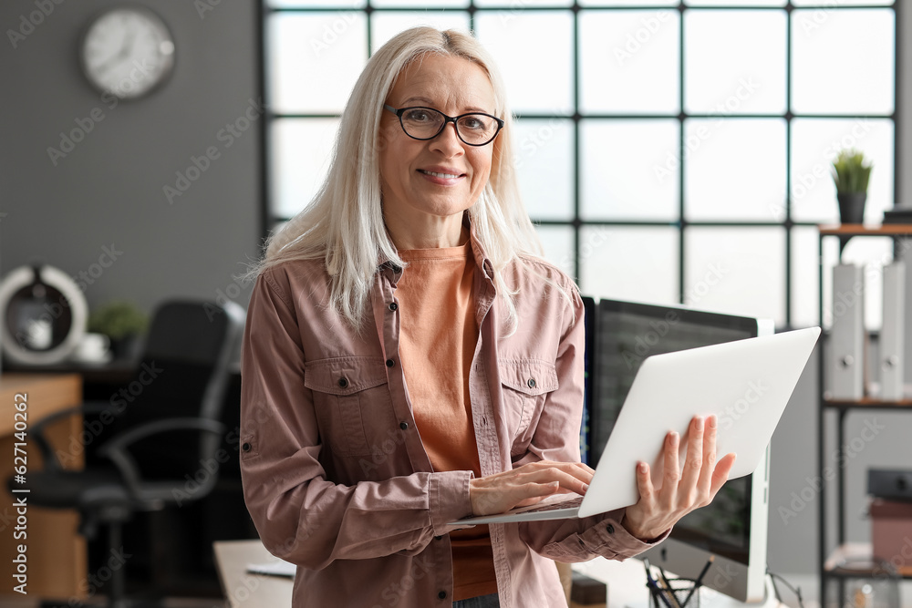 Mature female programmer working with laptop in office