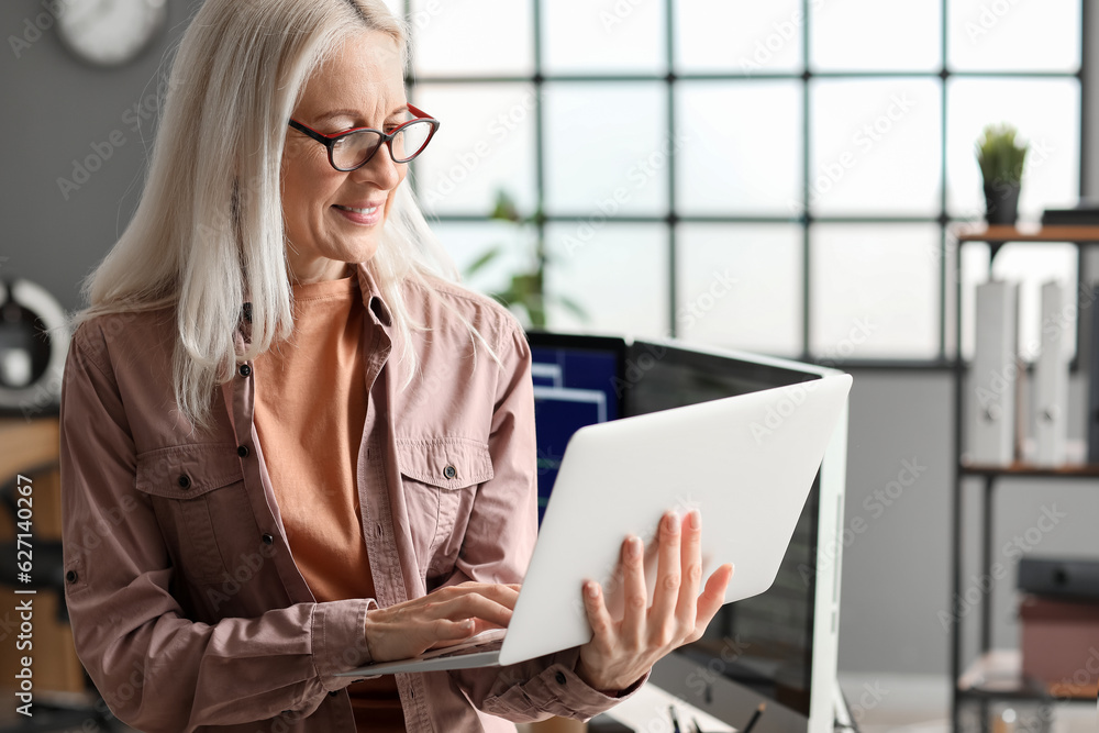 Mature female programmer working with laptop in office