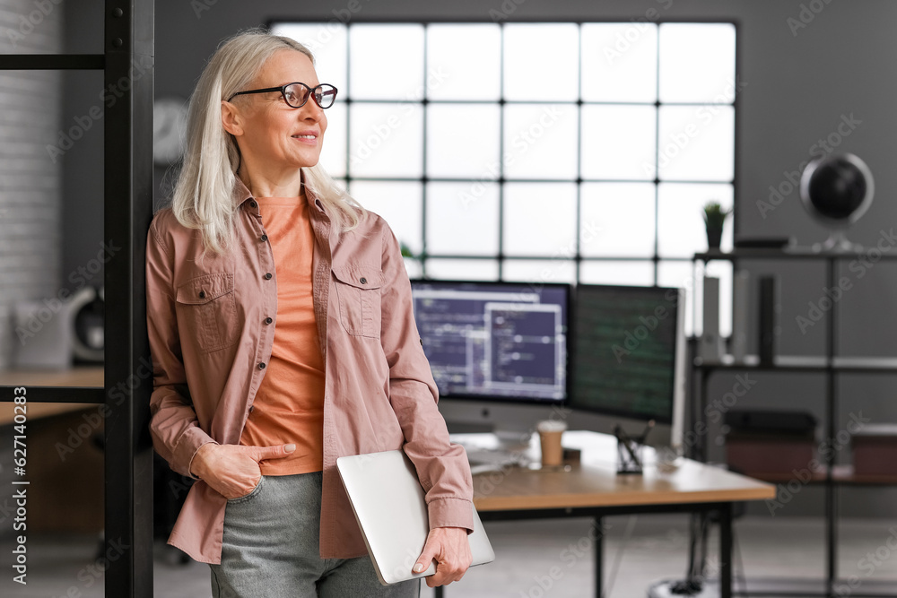 Mature female programmer working with laptop in office