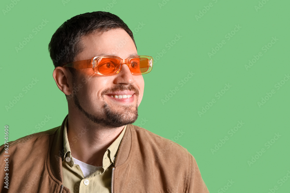 Handsome man in stylish sunglasses on green background, closeup